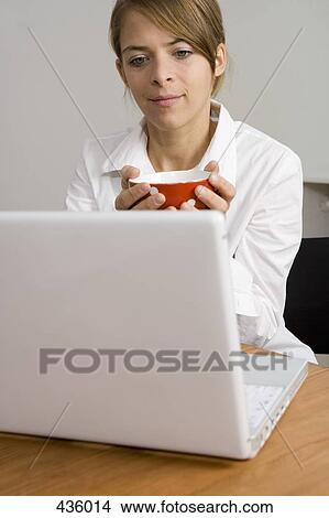 Picture - Woman sitting in front of laptop. Fotosearch