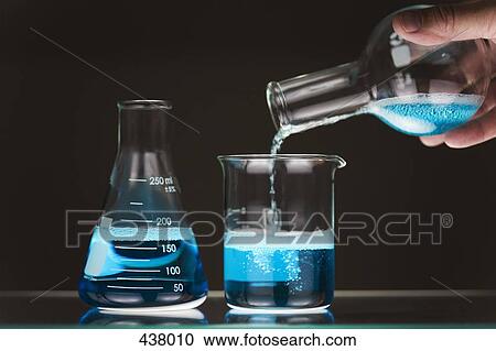 Stock Image - Close-up of a man pouring blue liquid into a beaker. Fotosearch