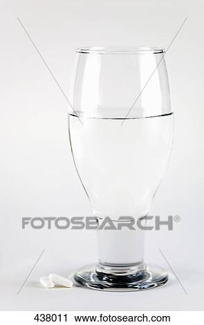 Two white tablets next to a glass of water View Large Photo Image Stock Image - Two white tablets next to a glass of water. Fotosearch