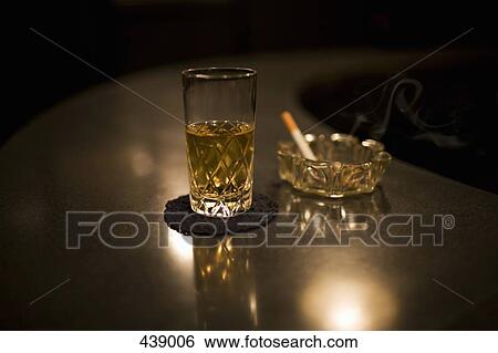 Glass of whiskey next to a cigarette in an ashtray View Large Photo Image Stock Photograph - Glass of whiskey next to a cigarette in an ashtray. Fotosearch