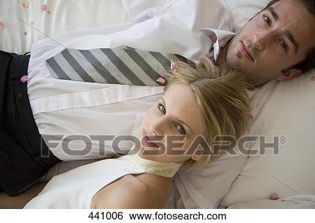 A bride and a groom lying down on a bed together View Large Photo Image Stock Photograph - A bride and a groom lying down on a bed together. Fotosearch