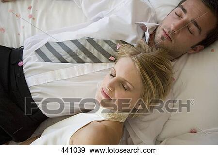 A bride and a groom resting on a bed together View Large Photo Image Stock Photo - A bride and a groom resting on a bed together. Fotosearch
