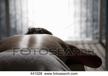 Stock Photo - A man lying down on a massage table. Fotosearch