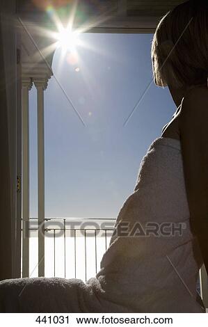 A woman sitting on a massage table wrapped in a towel and looking out to sea View Large Photo Image Stock Image - A woman sitting on a massage table wrapped in a towel and looking out to sea. Fotosearch