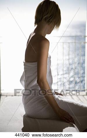 Stock Image - A woman wrapped in a towel and sitting on a massage table. Fotosearch
