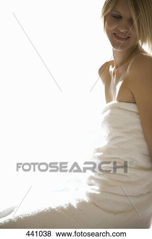 Stock Photo - A woman wrapped in a towel and sitting on a massage table. Fotosearch
