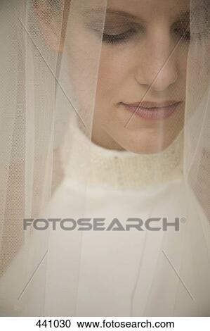 Stock Image - Close-up of a bride under a veil looking down. Fotosearch