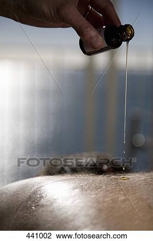 Stock Image - Close-up of a massage therapist pouring oil on a man's back. Fotosearch