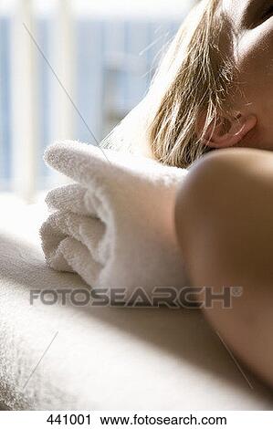 Stock Image - Close-up of a woman lying down on a massage table. Fotosearch
