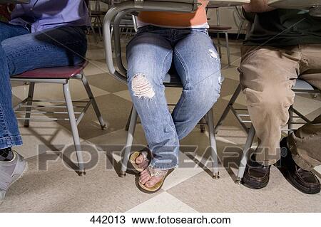 Stock Image - Low section view of students sitting at desks. Fotosearch