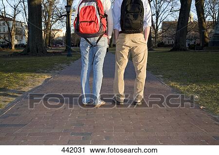 Stock Image - Rear view of two students outside of university. Fotosearch