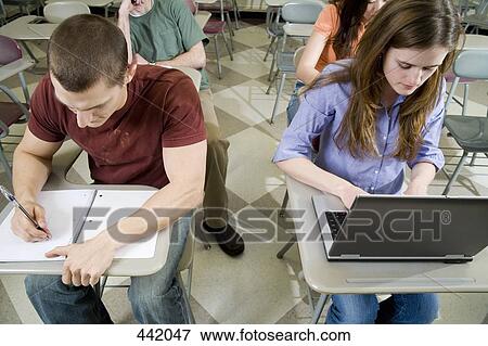Students sitting at desks and working View Large Photo Image Stock Photo - Students sitting at desks and working. Fotosearch