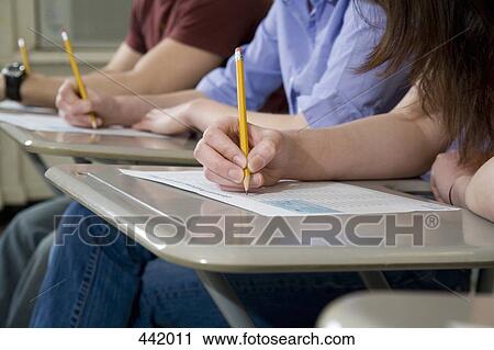 Stock Image - Students sitting at desks and writing. Fotosearch