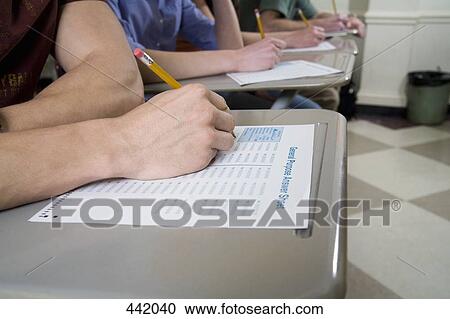 Stock Image - Students sitting at desks and writing. Fotosearch