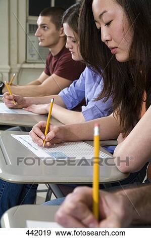 Stock Photo - Students sitting at desks and writing. Fotosearch