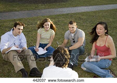 Stock Photo - University students sitting on grass with lecturer. Fotosearch