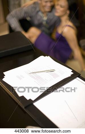 Paperwork on a desk and a couple embracing behind View Large Photo Image Stock Photo - Paperwork on a desk and a couple embracing behind. Fotosearch