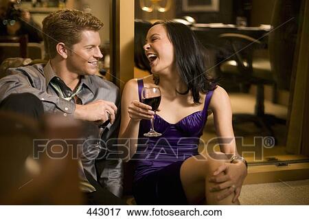 Stock Photo - Young couple sitting together in a hotel room and drinking wine. Fotosearch