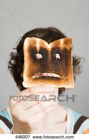 Woman holding burnt toast in front of face View Large Photo Image Stock Photo - Woman holding burnt toast in front of face. Fotosearch