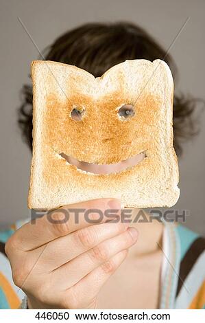 Stock Image - Woman holding toast in front of face. Fotosearch