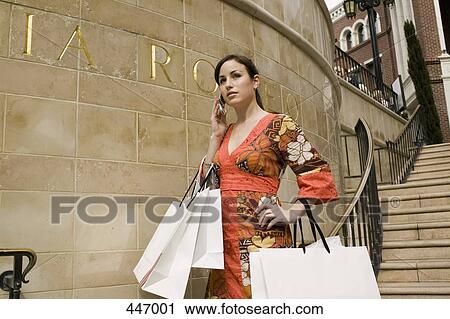 A woman using a mobile phone and holding shopping bags View Large Photo Image Stock Image - A woman using a mobile phone and holding shopping bags. Fotosearch