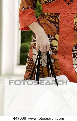Midsection of a woman holding shopping bags View Large Photo Image Stock Photograph - Midsection of a woman holding shopping bags. Fotosearch