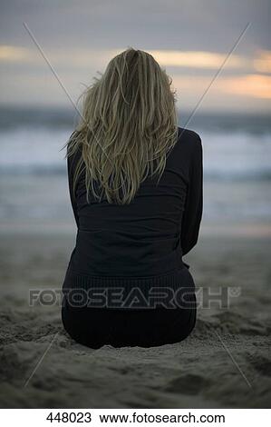 A woman sitting on a beach at sunset View Large Photo Image Stock Image - A woman sitting on a beach at sunset. Fotosearch