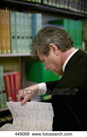 Businessman looking through a reference book View Large Photo Image Stock Photo - Businessman looking through a reference book. Fotosearch