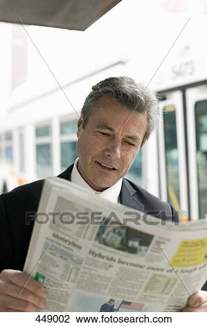 Businessman reading a newspaper at a bus stop View Large Photo Image Stock Image - Businessman reading a newspaper at a bus stop. Fotosearch
