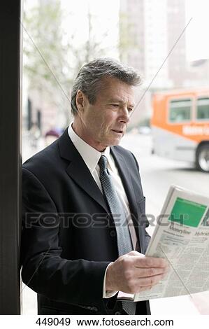 Businessman reading a newspaper at a bus stop View Large Photo Image Stock Photo - Businessman reading a newspaper at a bus stop. Fotosearch