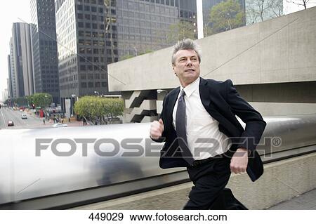 Businessman running along a walkway in the financial district View Large Photo Image Stock Photo - Businessman running along a walkway in the financial district. Fotosearch