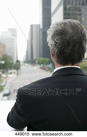 Businessman standing on a balcony in the financial district View Large Photo Image Stock Photography - Businessman standing on a balcony in the financial district. Fotosearch