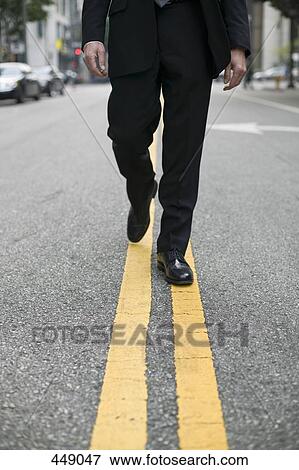 Stock Photo - Businessman walking along dividing line on a city street. Fotosearch