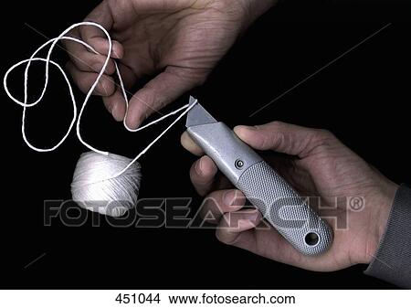 Man cutting string with a utility knife View Large Photo Image Picture - Man cutting string with a utility knife. Fotosearch