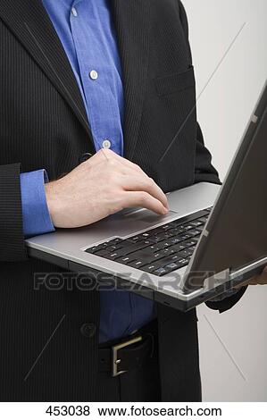 Stock Photo - Businessman standing and typing on a laptop computer. Fotosearch