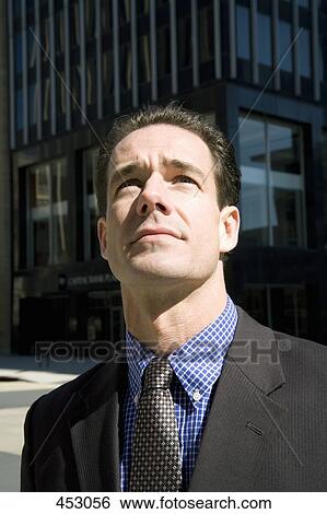 Businessman standing in the financial district and looking up View Large Photo Image Stock Photograph - Businessman standing in the financial district and looking up. Fotosearch