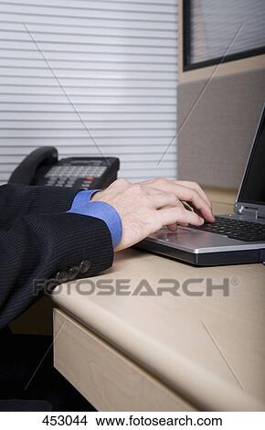 Close-up of a businessman at a desk using laptop View Large Photo Image Picture - Close-up of a businessman at a desk using laptop. Fotosearch