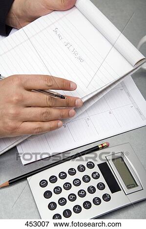 Close-up of a man at a desk with a notepad, pen, diary, calculator, and a pencil View Large Photo Image Stock Photo - Close-up of a man at a desk with a notepad, pen, diary, calculator, and a pencil. Fotosearch