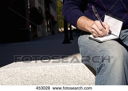 Man sitting on an outdoor bench and writing in a personal organizer View Large Photo Image Stock Photo - Man sitting on an outdoor bench and writing in a personal organizer. Fotosearch