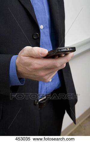 Midsection of a businessman holding a mobile phone View Large Photo Image Stock Photography - Midsection of a businessman holding a mobile phone. Fotosearch