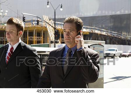 Two businessmen walking on sidewalk View Large Photo Image Stock Image - Two businessmen walking on sidewalk. Fotosearch