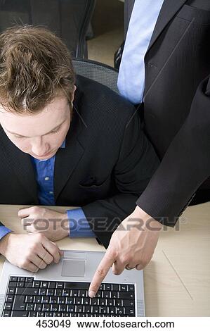 Stock Photo - Two businessmen working on a laptop. Fotosearch
