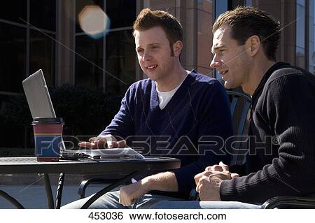 Two men looking at a laptop computer at an outdoor cafe View Large Photo Image Stock Photograph - Two men looking at a laptop computer at an outdoor cafe. Fotosearch