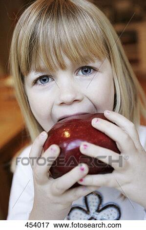 A young girl eating a red apple View Large Photo Image Stock Photo - A young girl eating a red apple. Fotosearch