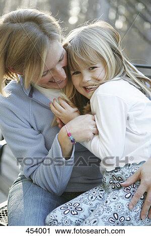 Mother and daughter embracing in a back yard View Large Photo Image Stock Image - Mother and daughter embracing in a back yard. Fotosearch