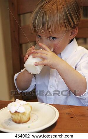 Young boy sitting at a table with a glass of milk and a cupcake View Large Photo Image Stock Image - Young boy sitting at a table with a glass of milk and a cupcake. Fotosearch