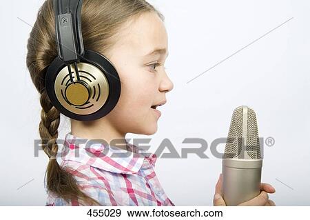 A girl wearing headphones and holding a microphone View Large Photo Image Stock Photo - A girl wearing headphones and holding a microphone. Fotosearch
