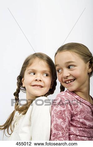 Two girls sitting back to back View Large Photo Image Stock Image - Two girls sitting back to back. Fotosearch