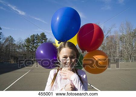Young girl holding helium balloons View Large Photo Image Stock Image - Young girl holding helium balloons. Fotosearch