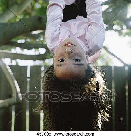 Stock Photography - Girl hanging upside down from a tree. Fotosearch